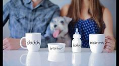 two people and a dog sitting at a table with coffee mugs in front of them