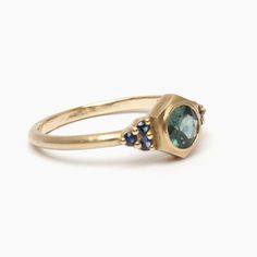 a gold ring with an oval blue topazte and two small diamonds on the side