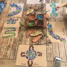 children are making beaded necklaces on the wooden table with papers and pictures next to them