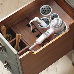 an open drawer with hairdryer and other items in it