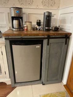 a small kitchen with a refrigerator and coffee maker on the counter, next to a rug