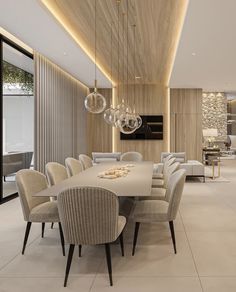 a large dining room table surrounded by beige chairs and chandelier hanging from the ceiling