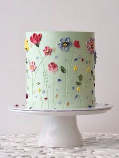 a green cake with flowers painted on the top and bottom is sitting on a white plate