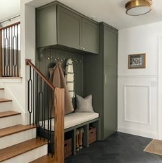 an entryway with stairs, storage cabinets and pillows on the bench next to it