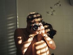 a man taking a selfie in front of a bathroom mirror with his camera attached to his neck