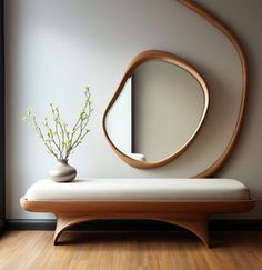 a vase with flowers sitting on a bench in front of a round mirror and wall