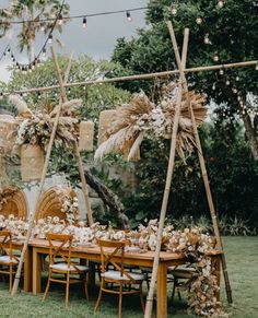 a wooden table topped with lots of flowers and greenery next to an outdoor dining area