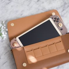 a cell phone in a leather case on a marble surface with white flowers and greenery