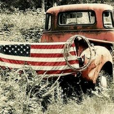 an old truck with the american flag painted on it's side in a field