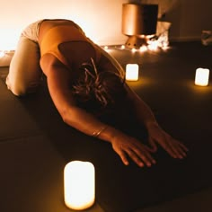 a woman laying on the floor with her head down in front of some lit candles