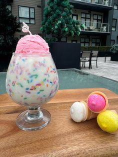 an ice cream sundae with sprinkles sits on a table next to other dessert items