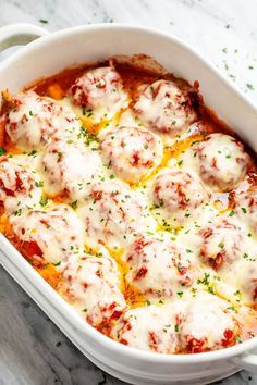 a casserole dish with meatballs and sauce in it on a marble table