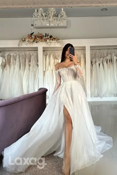 a woman in a white dress taking a selfie with her cell phone while standing next to a couch