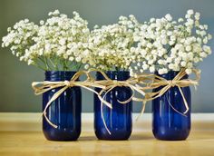 three blue vases with white flowers in them