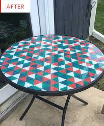 an outdoor table painted with geometric designs on the top and bottom, sitting in front of a door