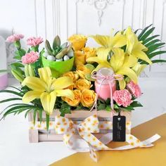 a bouquet of yellow and pink flowers in a wooden box with ribbon tied around it