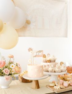 a table topped with cakes and desserts next to balloons in the air above them