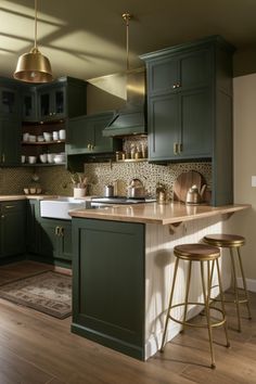 a kitchen with dark green cabinets and gold accessories on the countertop, along with two stools