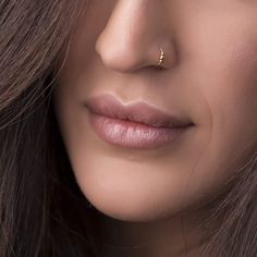 a close up shot of a woman's face wearing gold nose piercings