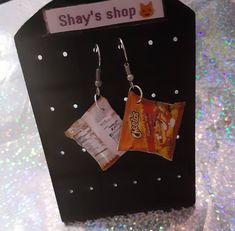 a pair of earrings hanging from hooks on a black box with silver flecks