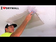 a man in yellow shirt and black hat painting a ceiling with white paint on it