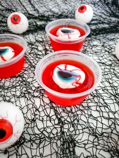 red cups with googly eyes are sitting on a black tablecloth covered table cloth