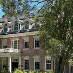 a large brick building with white trim and windows on the top floor is surrounded by trees