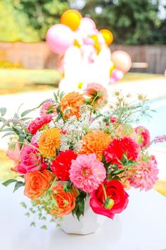 a vase filled with lots of flowers on top of a table next to a pool