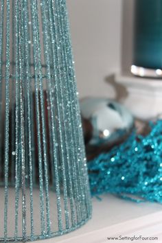 a blue tinsel christmas tree sitting on top of a white mantle