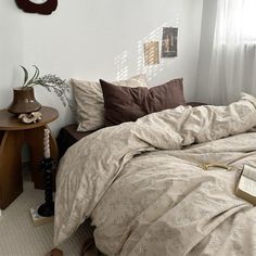 a bed sitting in a bedroom next to a table with a book on it and a clock above it