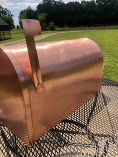 a large metal object sitting on top of a metal table next to a grassy field