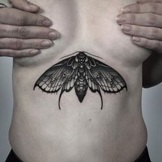 a man with a butterfly tattoo on his stomach holding his hands behind his back to show the chest area