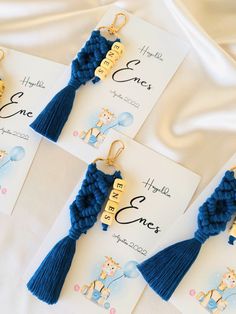 three blue tasselled earrings are on top of a white sheet with some cards