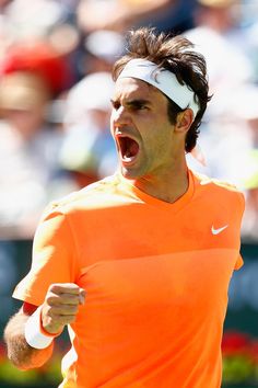 a male tennis player in an orange shirt is screaming