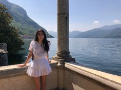 a woman standing on the edge of a balcony next to water