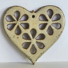 a ceramic heart shaped object with holes in the middle and petals cut out of it