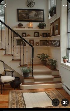 there is a staircase in the house with potted plants on it and pictures above