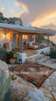 a house on the side of a cliff with a rug in front of it