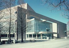 a large building with many windows and trees in front of it on a snowy day