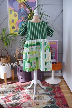 a mannequin wearing a green and white dress in front of a colorful rug