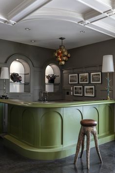 a green kitchen with stools and pictures on the wall