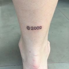 a woman's foot with the number 2000 tattooed on her left side calf area