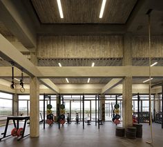 an empty gym with equipment in the middle and lots of windows on the side wall