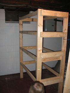 a child standing in front of a wooden bunk bed with no mattresses on it