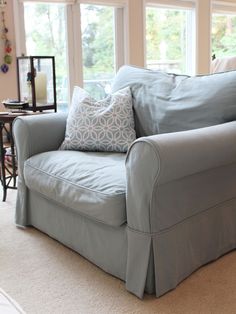 a blue couch sitting in front of two windows