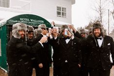 a group of men in tuxedos taking pictures with their cell phones on a snowy day