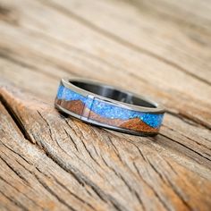 a wedding band with blue and brown inlays on an old wooden table top