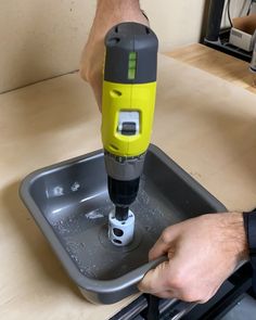 a man is using a drill to fix a hole in a tray on the counter