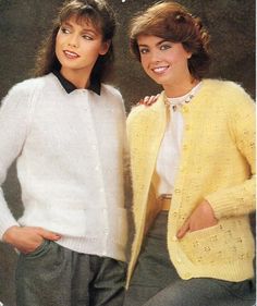 two women in sweaters and pants standing next to each other