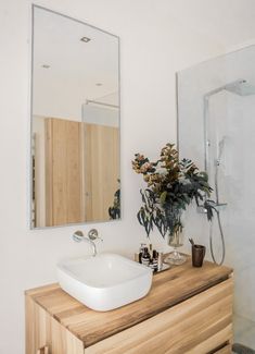 a bathroom sink sitting under a large mirror next to a walk in shower and wooden counter top